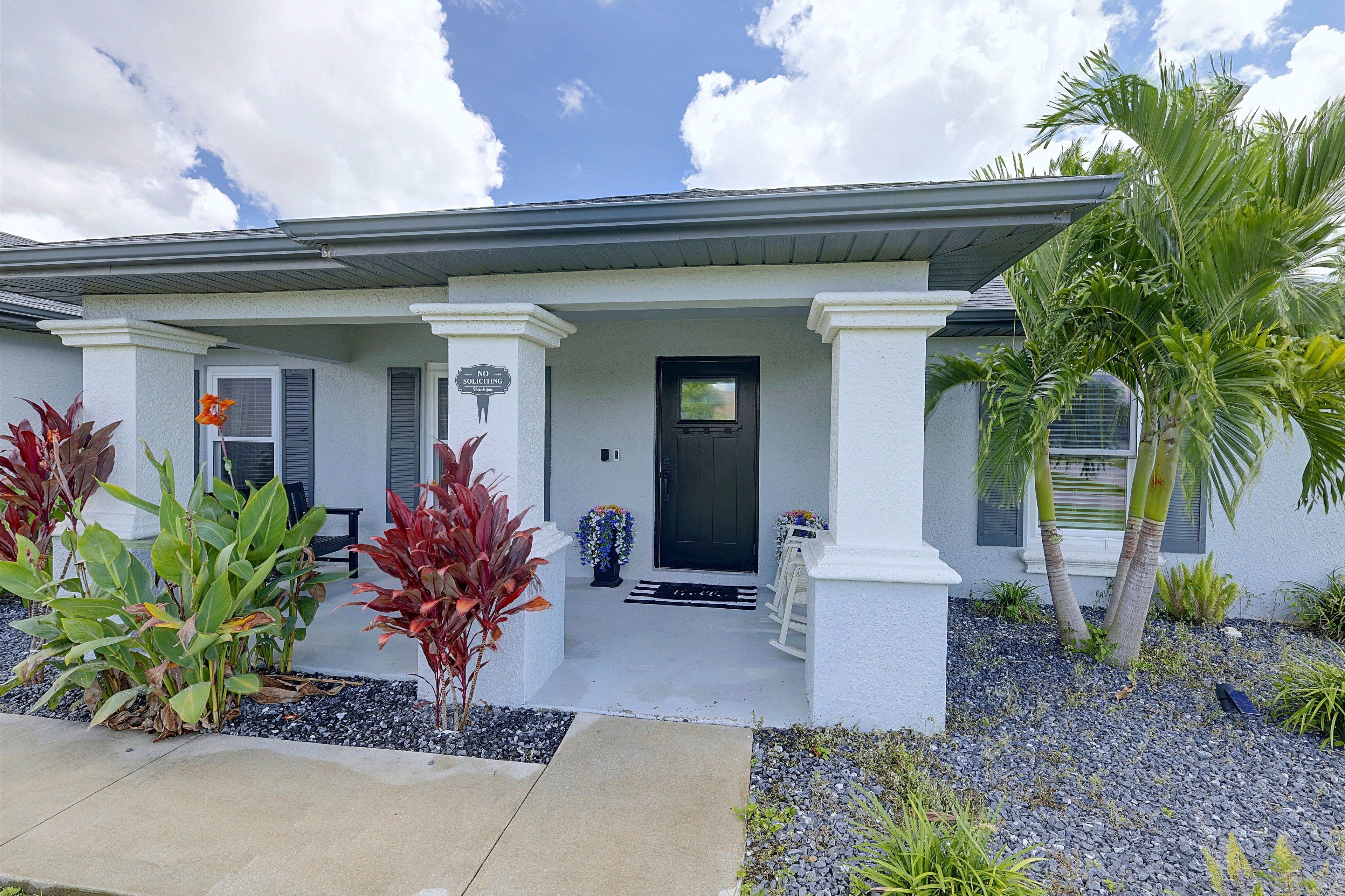 A residential house with a front porch, a black door, and a 'No Soliciting' sign.