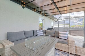 Ein Außenbereich mit Sitzgelegenheiten, einem Tisch mit Glasplatte, gepolsterten Sofas und Korbstühlen.