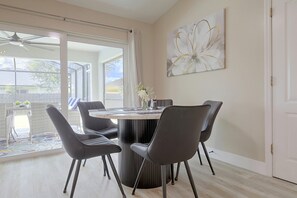 A dining area with a round table, four chairs, and a view through a glass door to the outside. - Florida Sunshine! Cape Coral Home w/ Pool (Cape Coral)