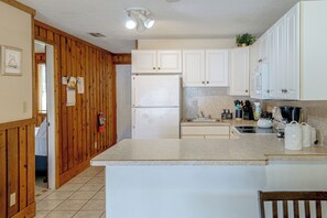 A kitchen with wooden paneling, white cabinets, a refrigerator, a sink, and a kettle on the counter. - License to Chill: Lake Access, 14 Mi to Disney (Clermont)