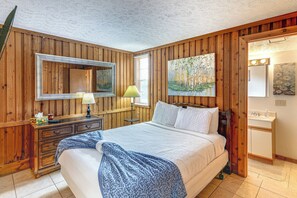 Ein Schlafzimmer mit einer Holzvertäfelung, einem Bett mit weißer Bettwäsche, einem Nachttisch mit Lampe und einem Bild über dem Bett.