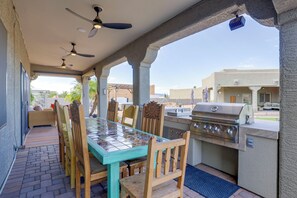 An outdoor patio with a glass-top table, wooden chairs, a grill, and ceiling fans. - Desert Hills Fenced Acre! Pool, Spa + Dogs Allowed (Phoenix)