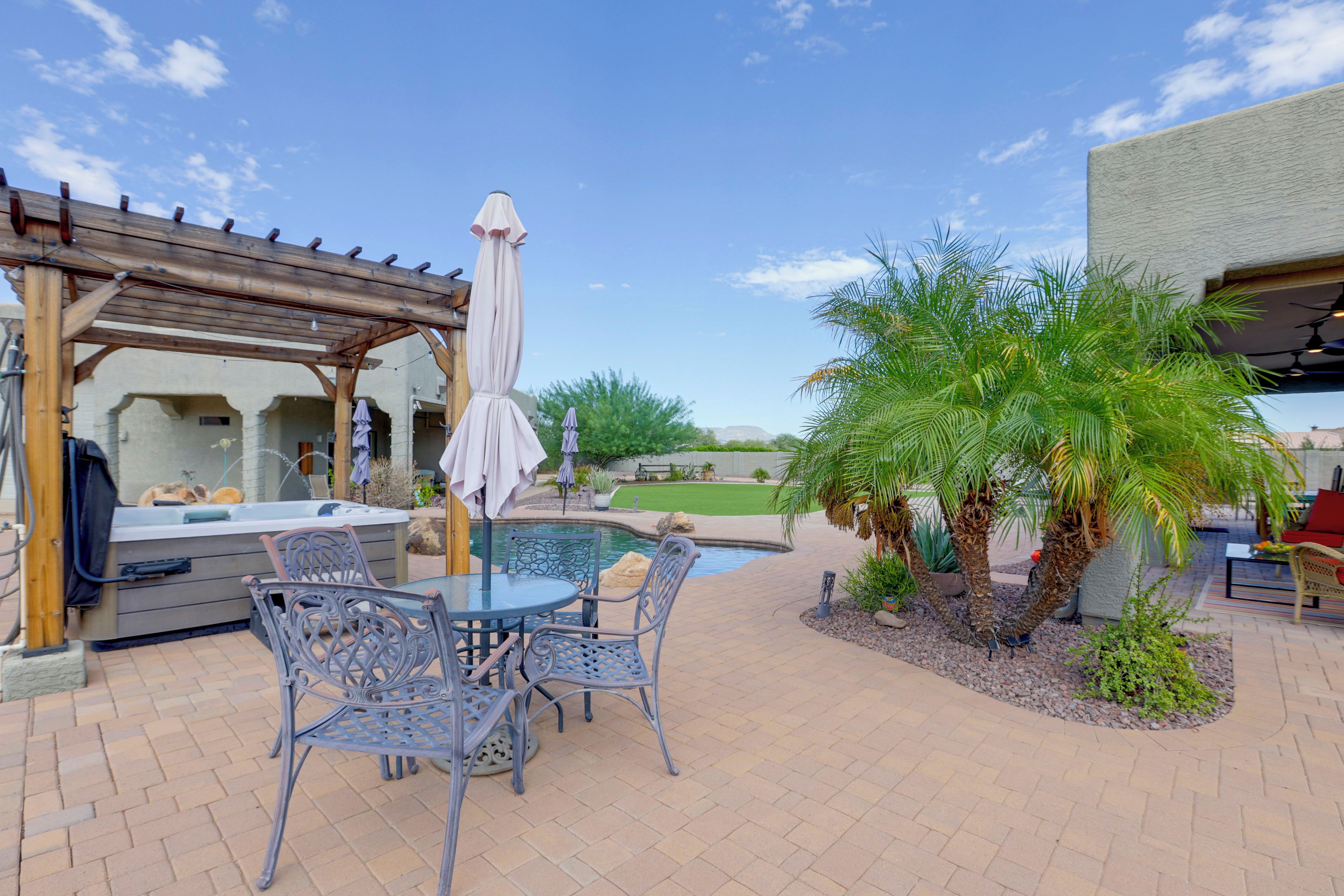 A patio area with a hot tub, outdoor seating, and a pool.