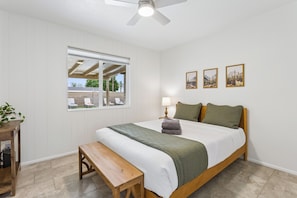 A bedroom with a bed, a bench, a window, and a ceiling fan. - Casa Ebenezer | 4BR Pool & Spa Near Old Town (Scottsdale)