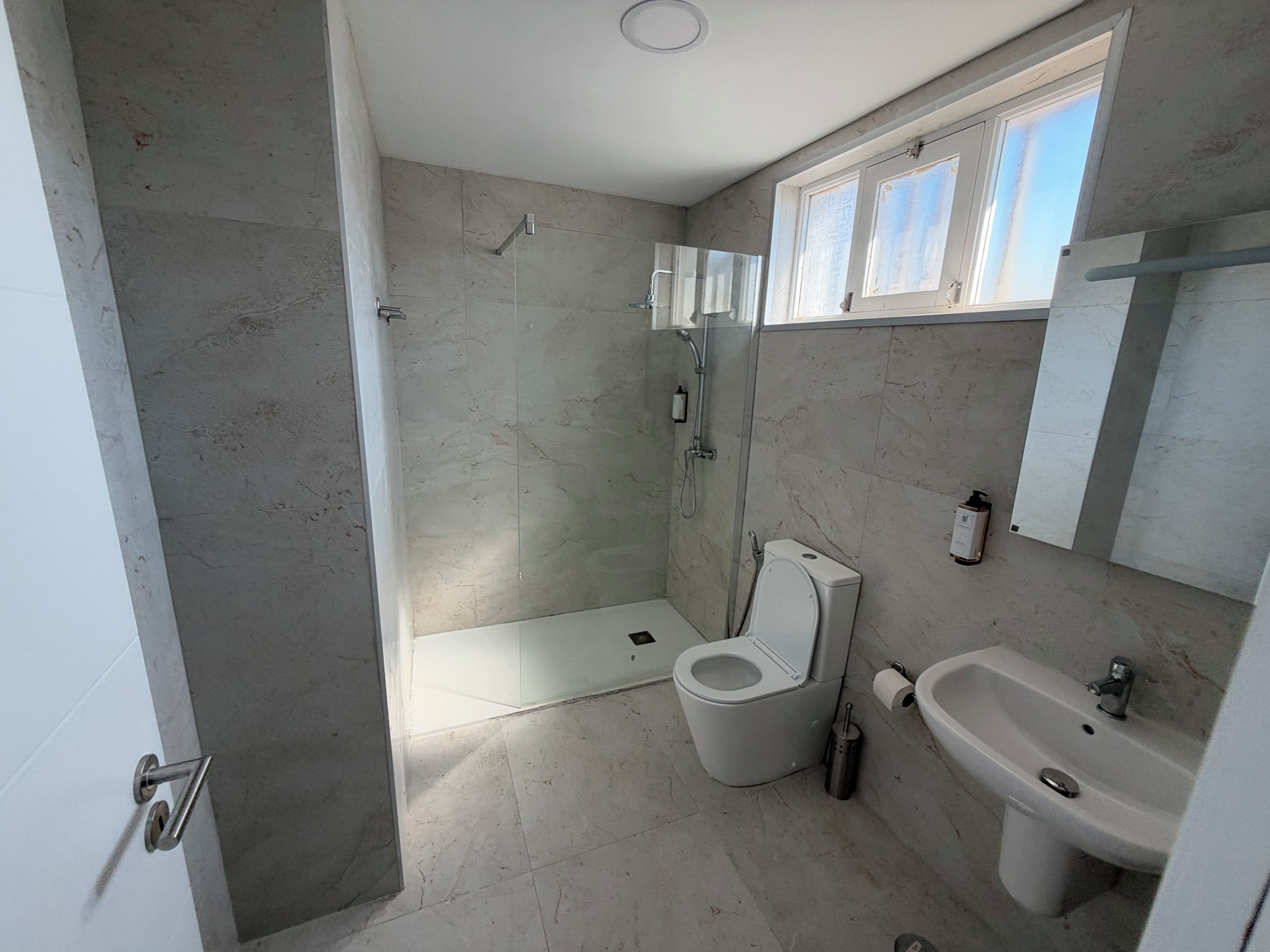 Une salle de bain avec une douche, des toilettes, un lavabo et une fenêtre.