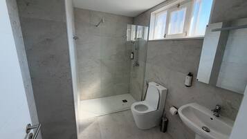 Une salle de bain avec une douche, des toilettes, un lavabo et une fenêtre.