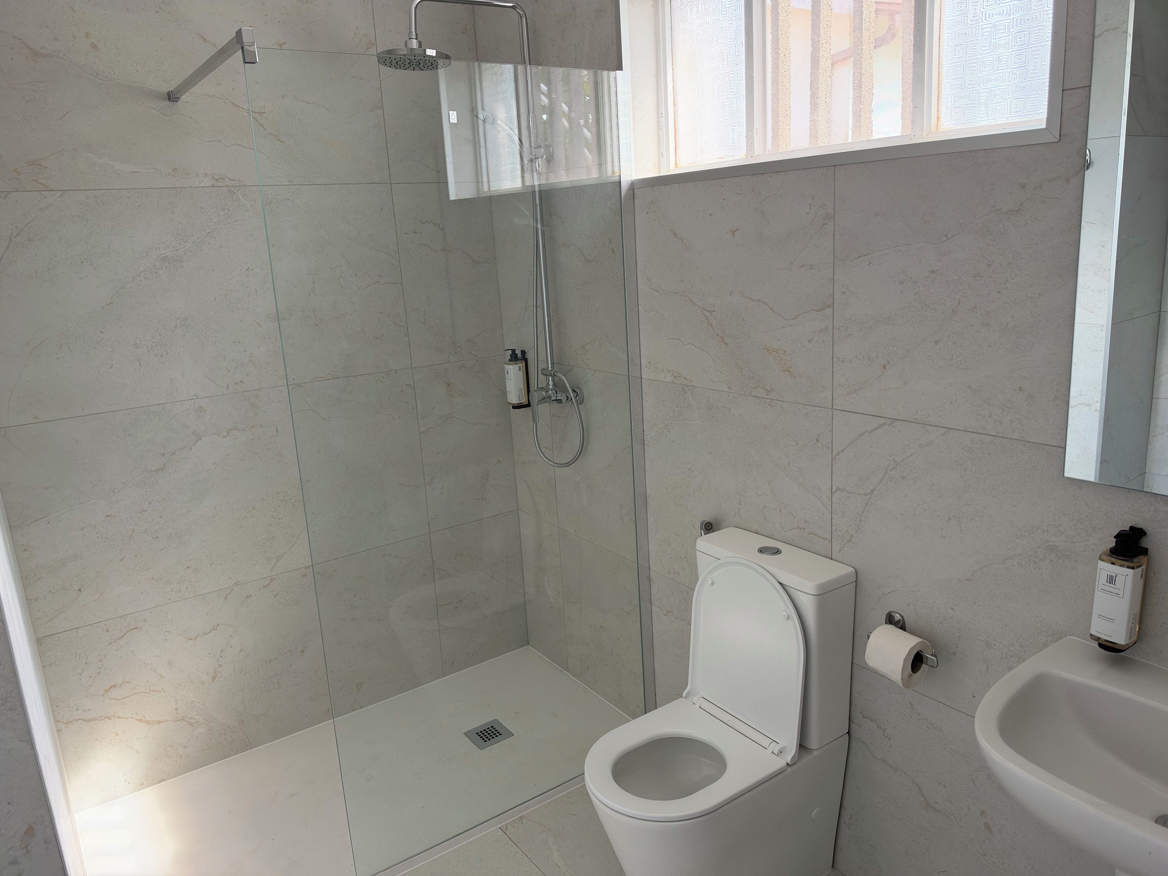 Et badeværelse med bruser, toilet og vask.