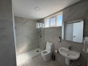 A bathroom with a shower, toilet, sink, and a window. - Alojamento Local Cova Da Serpe (Figueira da Foz)