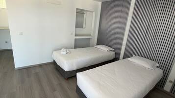 A modern hotel room with two single beds, a large mirror, and a striped wall.