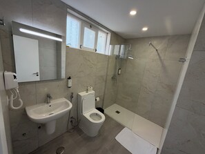 A modern bathroom with a sink, toilet, and shower.