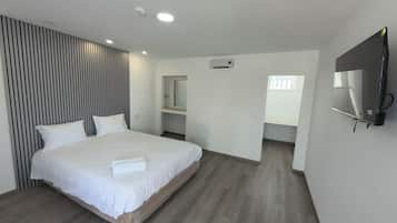 Une chambre d’hôtel moderne dotée d’un grand lit, d’un téléviseur à écran plat fixé au mur et d’un dressing.