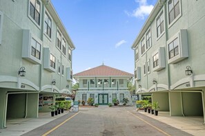 A building with a central entrance, potted plants, and a clear sky. - Family Getaway Near Disney With Pool and Games (Orlando)