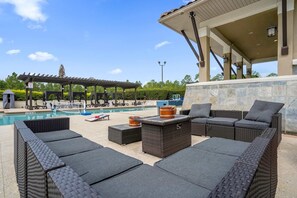 A poolside area with wicker furniture, a covered seating area, and a view of the pool. - Family Getaway Near Disney With Pool and Games (Orlando)