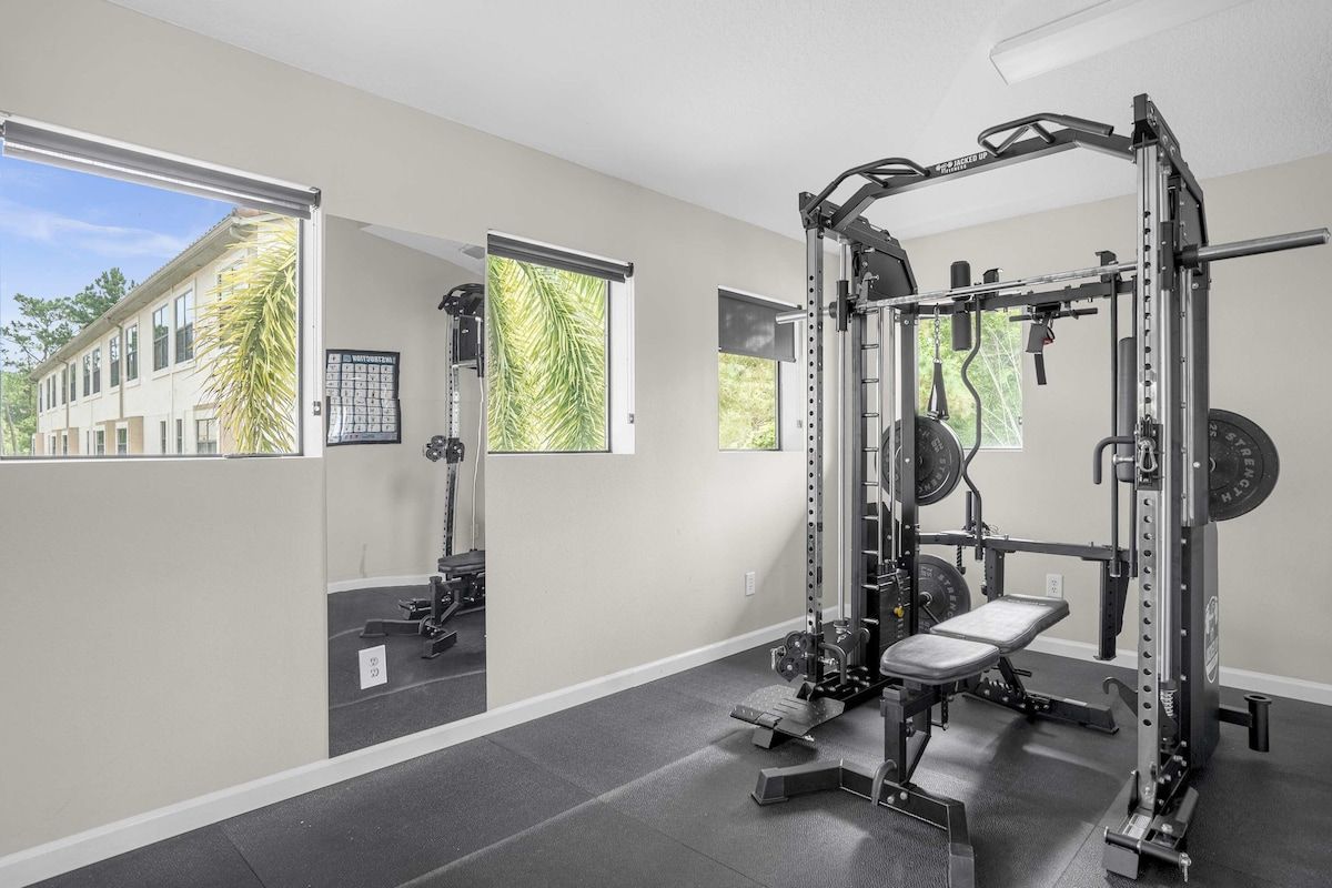 Un gimnasio con una estructura para sentadillas, banco y discos de pesas.