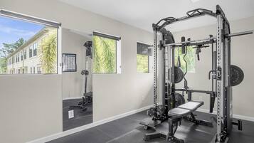Un gimnasio con una estructura para sentadillas, banco y discos de pesas.