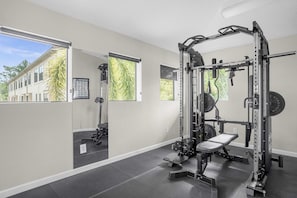A gym with a squat rack, bench, and weight plates. - Group Disney Stay With Pool Spa Game Amenities (Orlando)