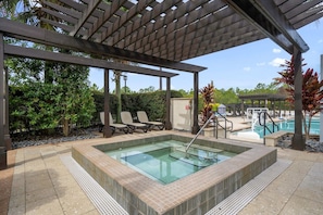 A pool area with a hot tub, lounge chairs, and a covered seating area. - Group Disney Stay With Pool Spa Game Amenities (Orlando)