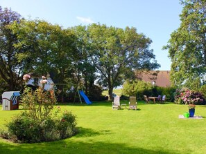 A backyard with a swing set, a slide, and a small table with chairs. - Holiday Apartment With 1 Bedroom (Witsum)