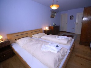 A double bed with a wooden headboard, a bedside table with a lamp, and a small nightstand. - Holiday Apartment With 1 Bedroom (Witsum)