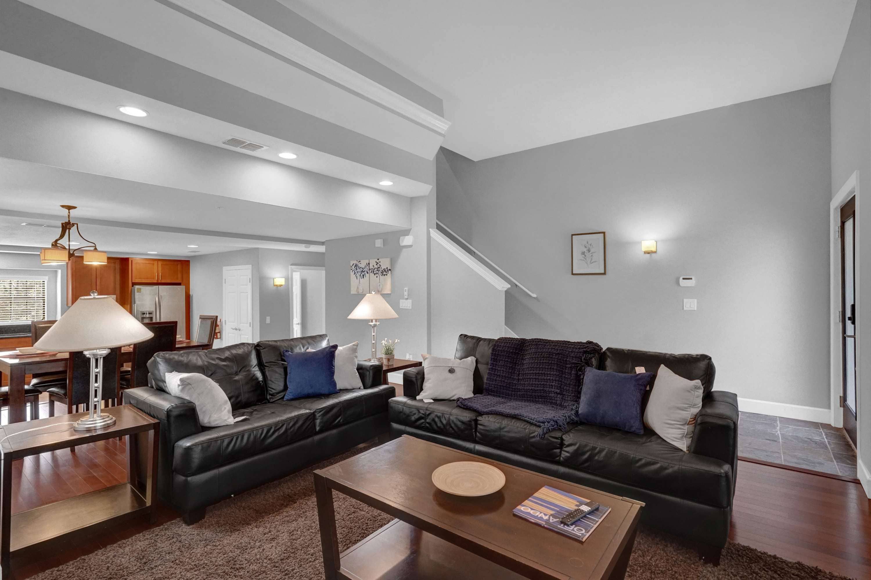 Uma sala de estar moderna com um sofá seccional, uma mesa de centro e um espaço de refeições com uma luminária.