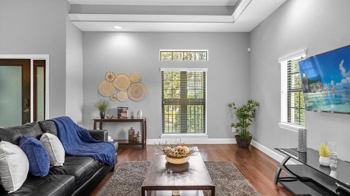A living room with a black leather sofa, a coffee table, and a TV on a stand.