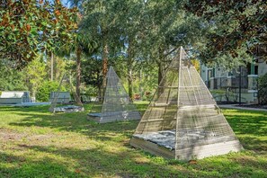 Estruturas geométricas ao ar livre com assentos, cercadas por árvores e grama.