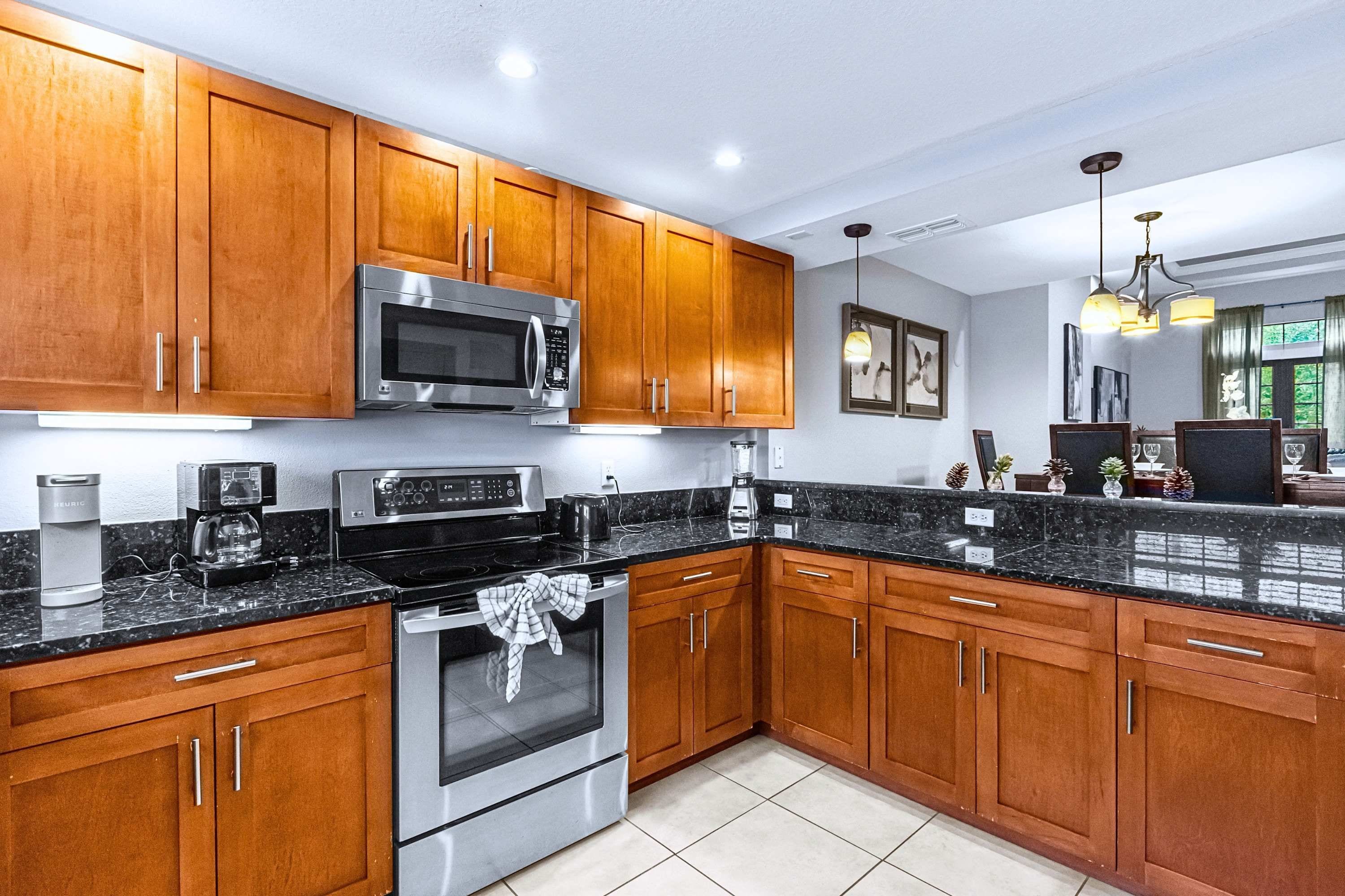 A modern kitchen with wooden cabinets, stainless steel appliances, and a granite countertop.