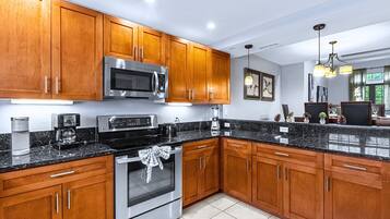 A modern kitchen with wooden cabinets, stainless steel appliances, and a granite countertop.