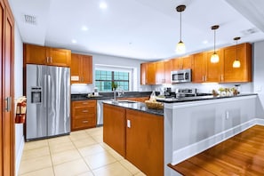 Una cocina moderna con armarios de madera, electrodomésticos de acero inoxidable e iluminación colgante.