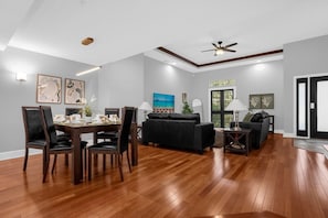 A spacious living area with a dining table, chairs, a sofa, and a ceiling fan. - Home Near Disney With Resort Pool Spa Access (Orlando)