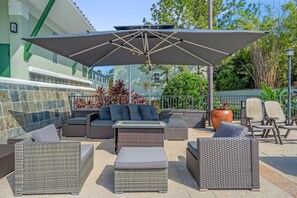 An outdoor seating area with a large umbrella, wicker furniture, and a potted plant. - Home Near Disney With Resort Pool Spa Access (Orlando)