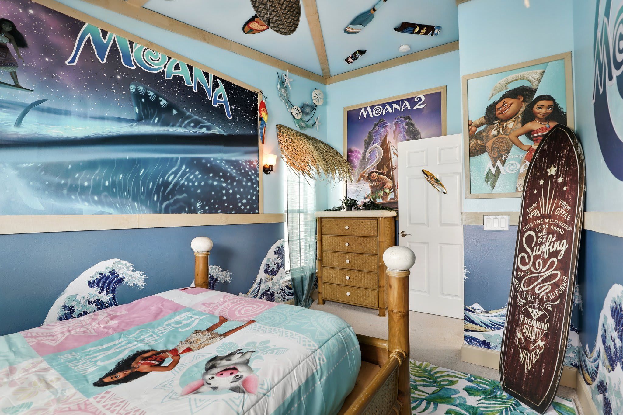 Un dormitorio con cama, cómoda y adornos en la pared, incluyendo una tabla de surf y carteles de películas.