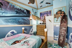 A bedroom with a bed, a dresser, and wall decorations including a surfboard and movie posters. - Magical Townhome Near Disney w Resort Pool Access (Orlando)