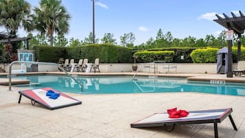 Una piscina con sillas de descanso y una cancha de baloncesto.