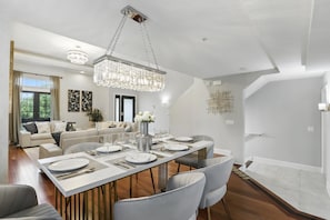 Área de refeições moderna com uma mesa comprida posta para quatro pessoas, rodeada por assentos confortáveis.