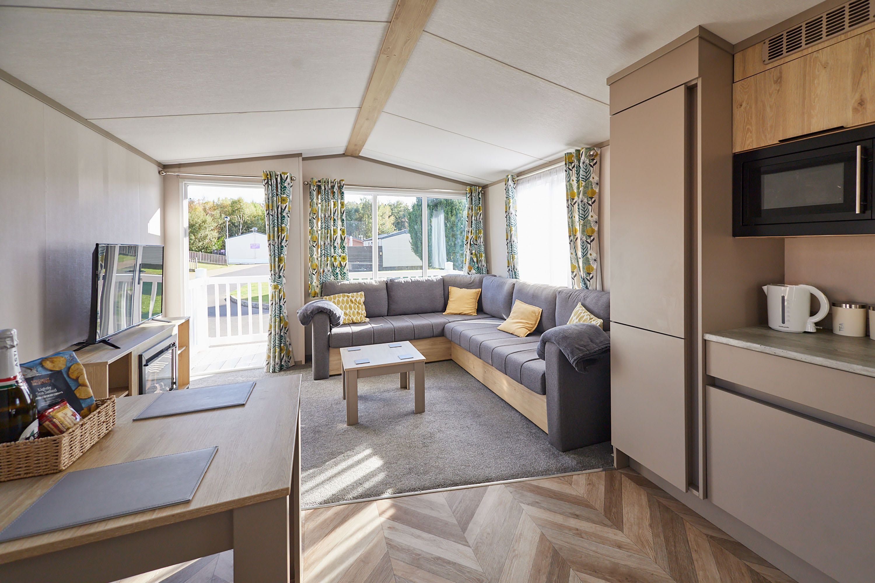 A compact living space with a sofa, a coffee table, a TV, and a kitchenette.