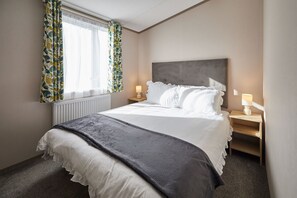 A hotel room with a bed, a nightstand, a window with curtains, and a radiator. - Host Stay Butterfly Retreat (Morpeth)