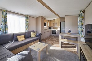 A compact living space with a sofa, a small table, a kitchenette, and a dining area. - Host Stay Butterfly Retreat (Morpeth)