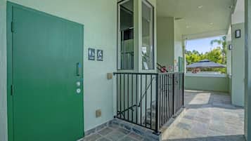A building exterior with a green door, a baby changing area sign, and a staircase leading to a covered outdoor area.