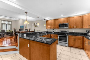 A modern kitchen with granite countertops, stainless steel appliances, and wooden cabinets. - Family Vacation Home Near Disney w Pool Spa (Orlando)