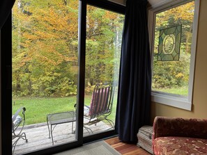 A room with a large window, a chair, a sofa, and a wooden deck outside. - 2BR condo w/ fireplace, ski locker, pool, sauna, tennis (Waitsfield)