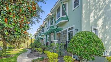 A row of townhouses with a green facade, a curved pathway, and well-maintained landscaping.