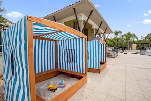 A beach-themed play area with striped tents and a sandy play space. - Vacation Home Near Disney With Resort Pool Gym (Orlando)