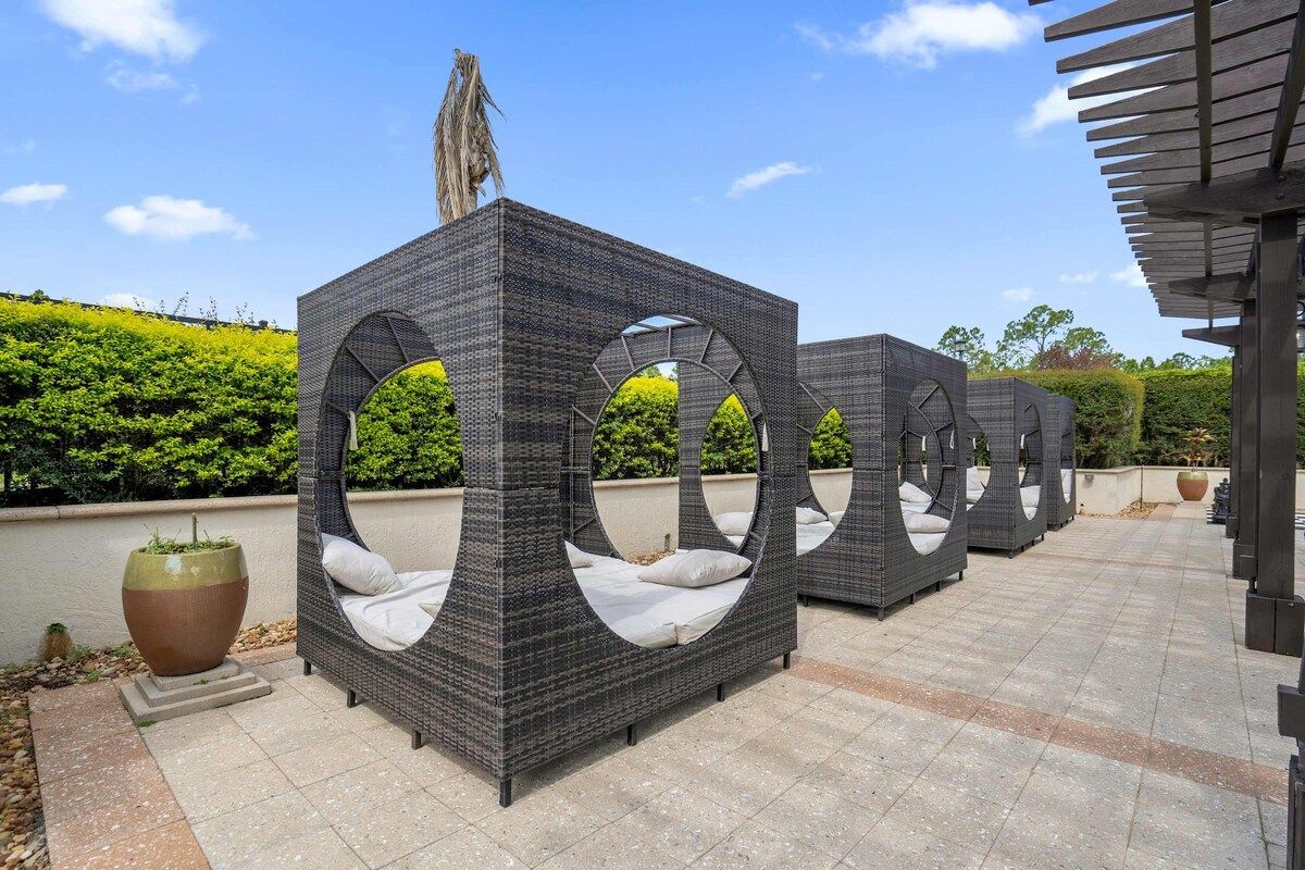 Outdoor wicker furniture with circular cutouts, a large planter, and a pergola structure.