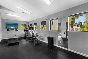 Un gimnasio con cintas de correr, bicicletas estáticas y una máquina de remo.