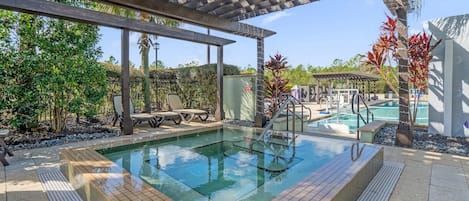 A pool area with a pergola overhead, a lounge chair, and a small pool.