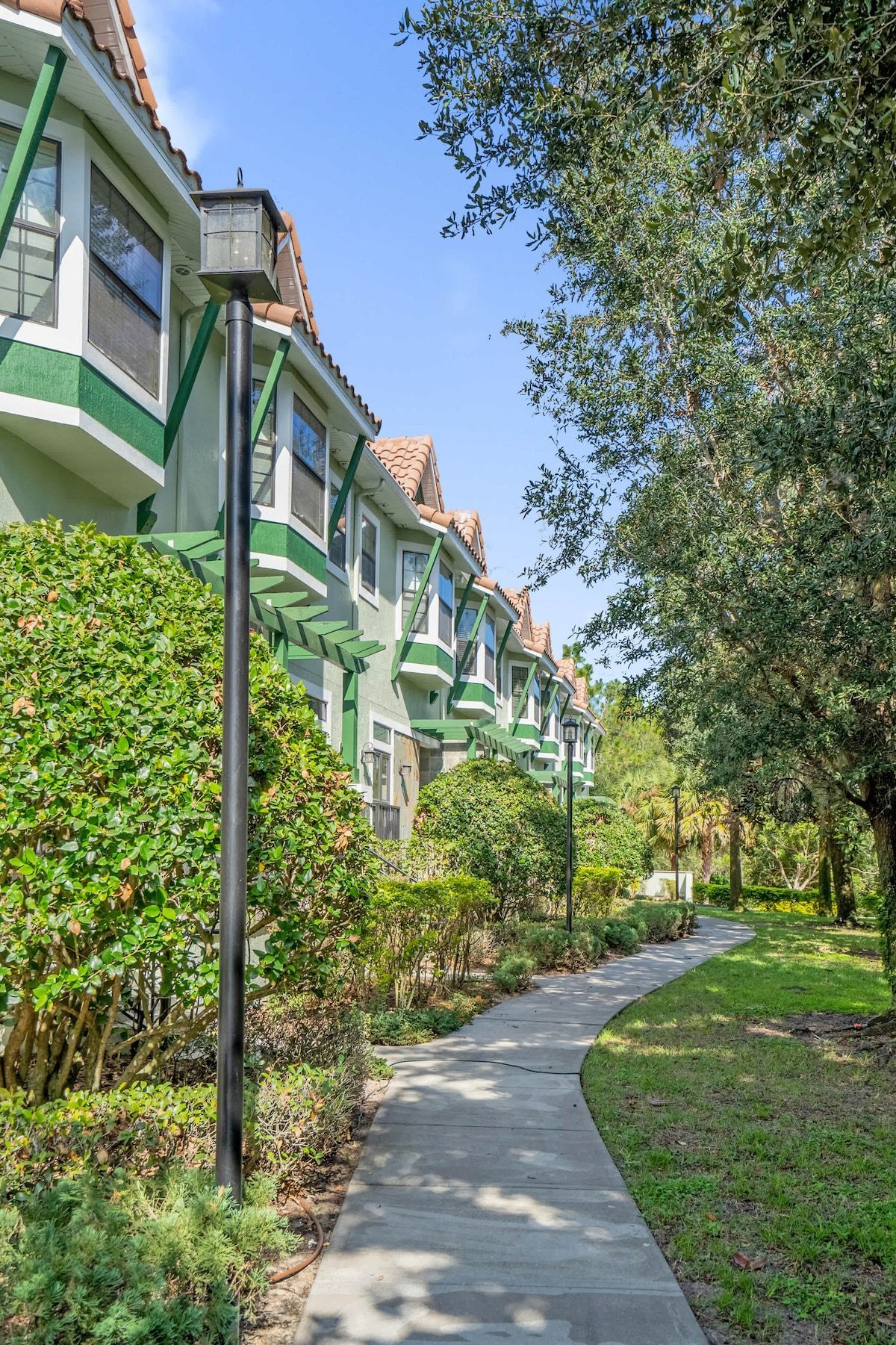 A residential area with a pathway leading to a row of houses with green and white trim.