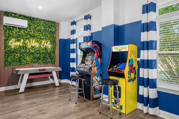 A room with arcade machines, a neon sign, and a green wall. - Casa Bella | Family Coastal Retreat | Ocean Views (Myrtle Beach)