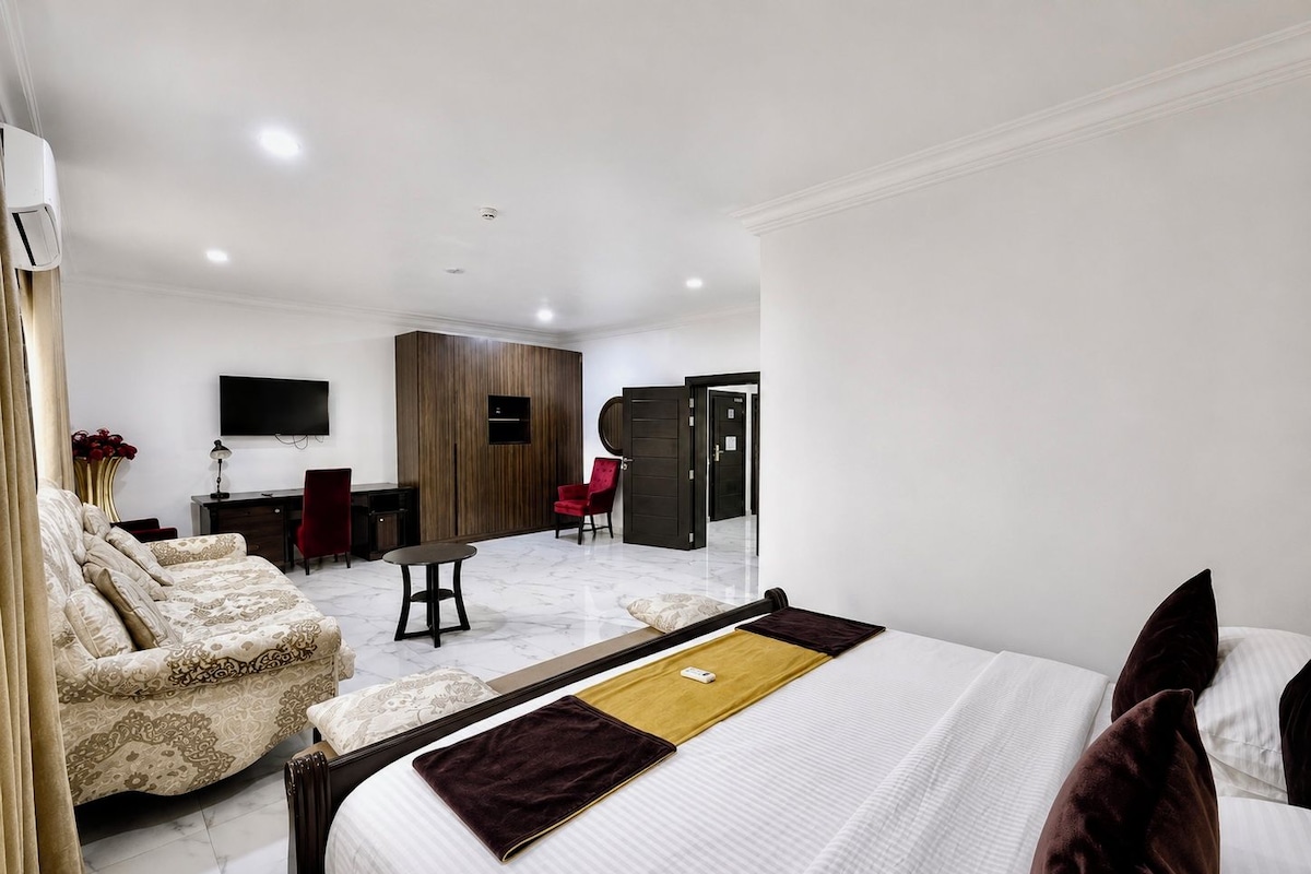 Een moderne hotelkamer met een bed, een bureau, een stoel en een televisie.