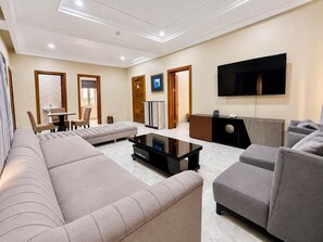Una sala moderna con un conjunto de sofá, una mesa de centro, un televisor de pantalla plana y un mostrador de recepción.